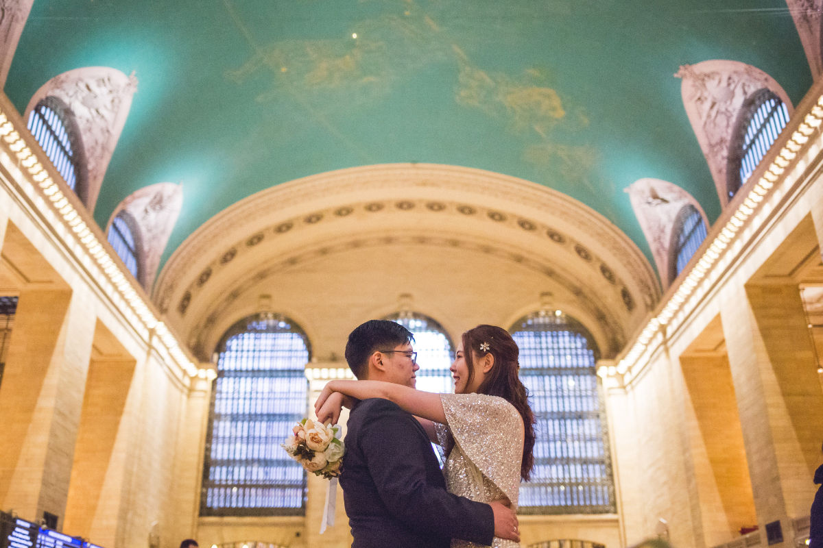 Couple embraces beneath the iconic ceiling of Grand Central Station after their New York winter wedding.